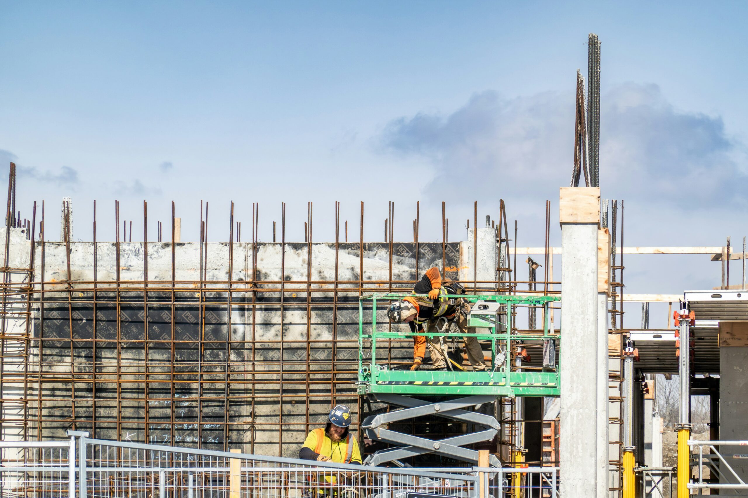 Construction workers using a scissor lift at an active commercial construction site.