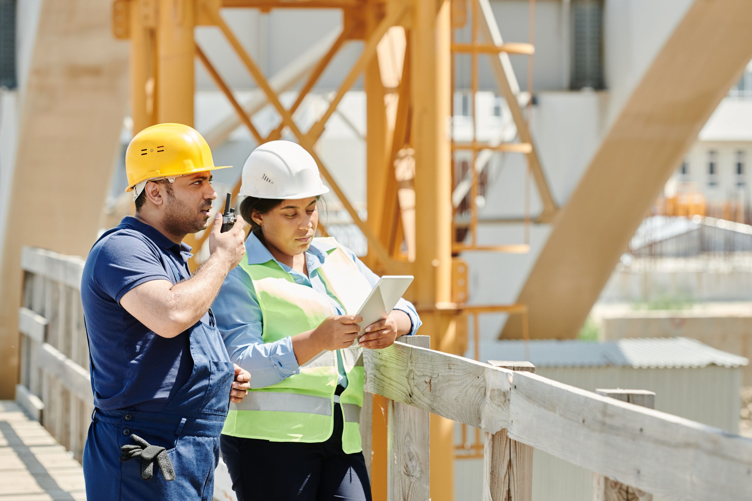 Construction professionals reviewing project information on a tablet at an active jobsite.